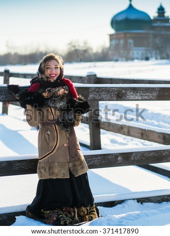 Russian noblewoman in Russian national clothes on a strong frost in the village near the fence