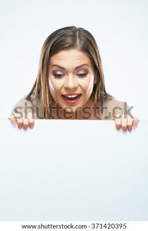 Woman looks out from behind white blank sign board. White background isolated.