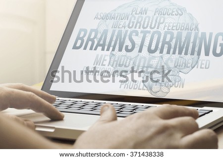 brainstorming concept: man using a laptop with brainstorming on the screen. Screen graphics are made up.