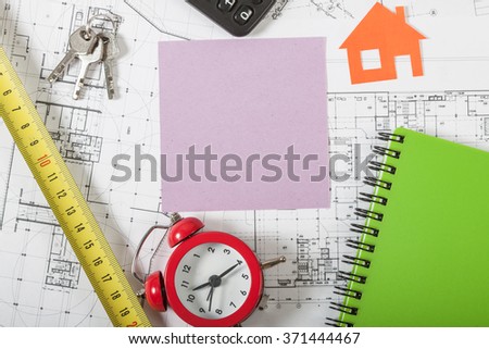 Model house on construction plan for house building, keys, red alarm clock and calculator. With pink blank business card. Real Estate Concept.