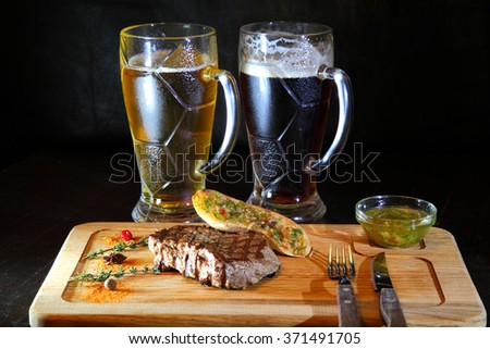 Steak and beer. Delicious steak. Beef steak medium rare on vegetable cushion. Grilled meat - Stock Image