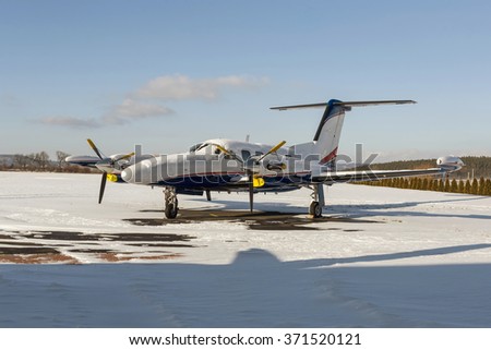 Twin engine aircraft with turboprop power plant on runway under snow in sunny winter day. Royalty-Free Stock Photo #371520121