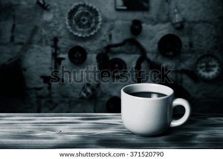 Coffee in cup on wooden table opposite defocused vintage background. Toned.