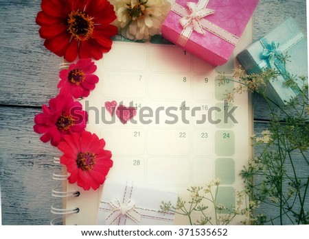 Calendar page with two red hearts on February 14 and red flowers with gift boxes concept for Valentines day