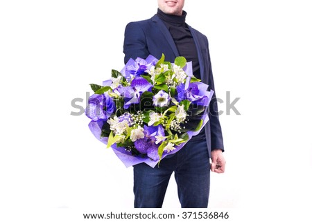 funny handsome young man with dark suit with a beautiful bouquet in the hands of white and purple flowers isolated on a white background
