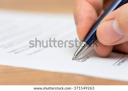 closeup of pen and human fingers  signing document
