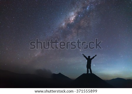 Man is spreading hand on hill and seeing the Milky Way. Royalty-Free Stock Photo #371555899