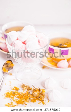 two cups of tea with pastel meringue and yellow flowers