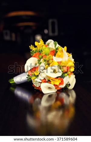 orange bridal bouquet with white callas on a table 