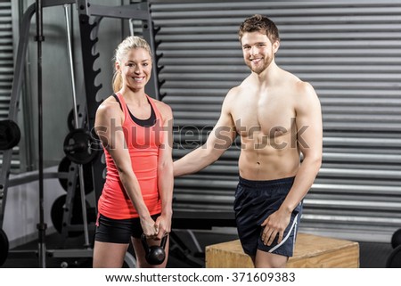 Couple exercising with dumbbells at crossfit gym