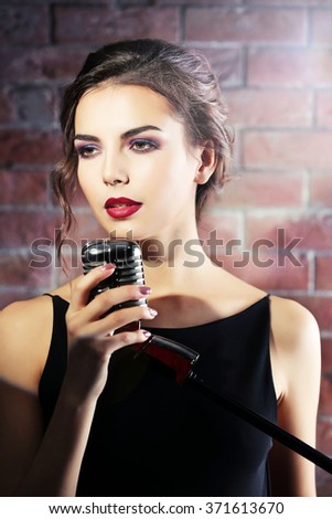 Attractive singing woman  on brick wall background, close up