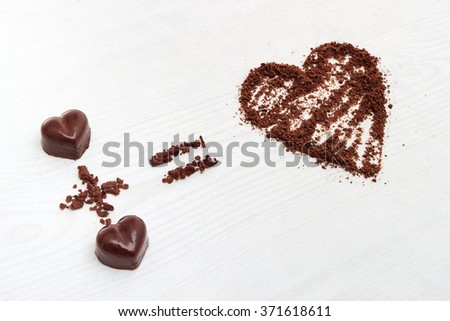 Love formula concept. Two chocolate candies make big love for chocolate. Horizontal view against wooden background