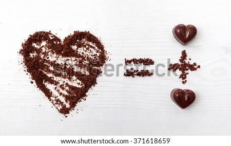 Love formula concept. Two chocolate candies make big love for chocolate. Horizontal top view against wooden background