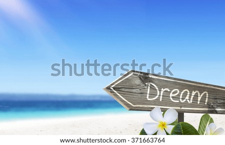 Dream wooden sign and blurry white sand beach background with frangipani flowers. Ocean and sunshine