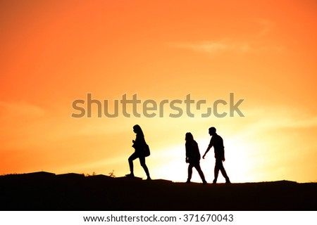 SIlhouette of a group of people walking at sunset on a hill