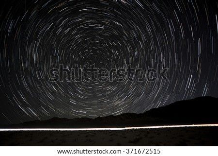 Star Trails in the desert at Death Valley with vehicle headlights passing through