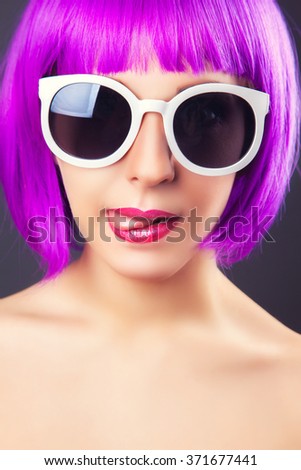 beautiful woman wearing colorful wig against gray background