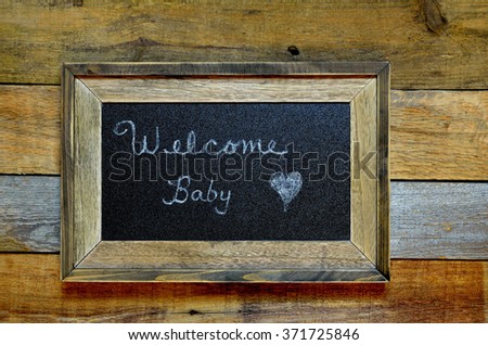Welcome baby announcement, written on  a rustic framed blackboard.  Concept of arrival of a newborn.