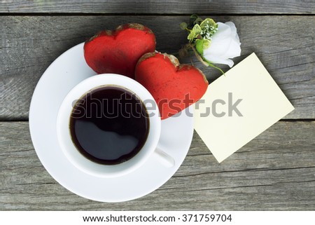 Romantic breakfast. Cup of coffee two heart shape red cookies, white rose note for text. Toned image