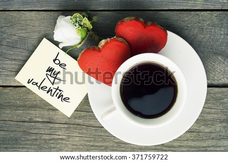Romantic breakfast. Cup of coffee two heart shape red cookies, white rose note with be my valentine message. Toned image