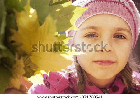 portrait of a little girl and autumn leaves in the city