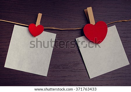 Red hearts hanging with two pieces of paper on the clothesline. Empty space for text. Valentines Day background with hearts. Valentine's Day theme. Toned image.