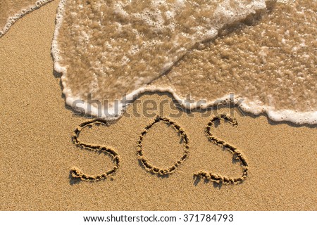 SOS - word drawn on the sand beach with the soft wave.   Royalty-Free Stock Photo #371784793