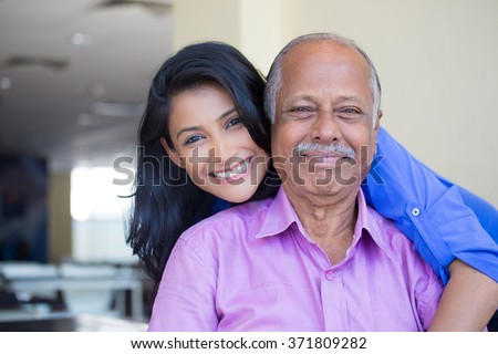 Closeup portrait, family, young woman in blue shirt holding older man in pink collar button down from behind, happy isolated indoors home background Royalty-Free Stock Photo #371809282