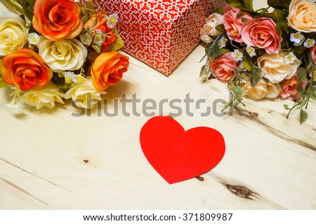Empty red heart paper note put on wooden desk with decorate by bouquet and gift box