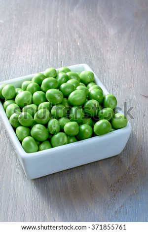 Fresh Peeled Green Peas in a white bowl on a wooden background, Selective Focus.