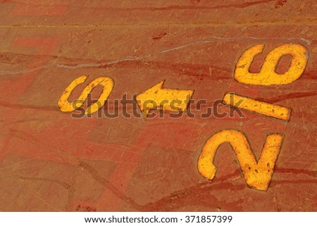 Numbers and lines in yellow brown sheet metal, closeup of photo