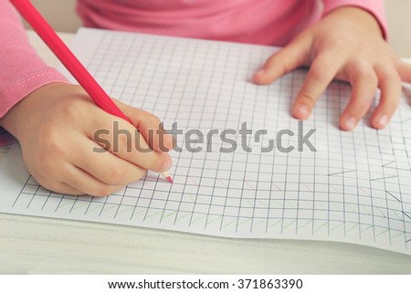 Child drawing with red pencil on paper, closeup