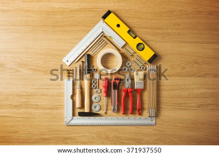 Conceptual house composed of DIY and construction tools on hardwood flooring, top view Royalty-Free Stock Photo #371937550