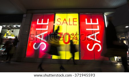 Sale signs in shop window, include silhouette of shoppers
