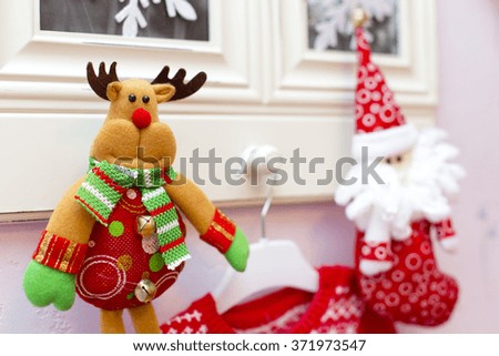 Toy green and red deer and santa hanging on white 