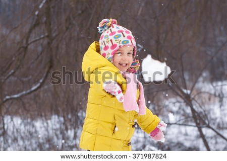 Little girl throwing snowball  in the winter park