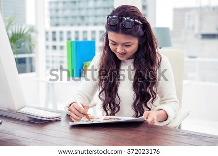 Smiling Asian woman looking at documents in office
