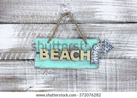 Mint green BEACH sign with metal arrow hanging on antique rustic white wood background