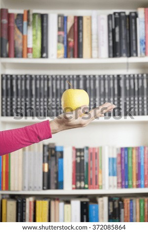 yellow apple on hand pink jersey over library background