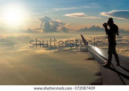 silhouette of photographer taking photo on airplane wing, Challenge business concept