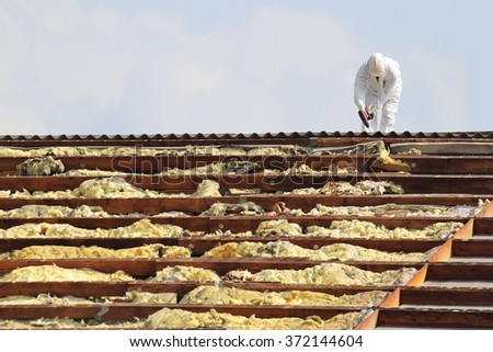 workman at rooftop of building being remediated Royalty-Free Stock Photo #372144604