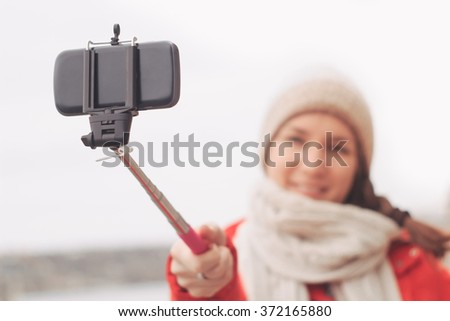 Woman using self stick taking photo with cellphone