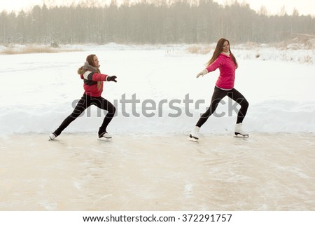 Coach of figure skating with apprentice practiced at the frozen lake in the winter