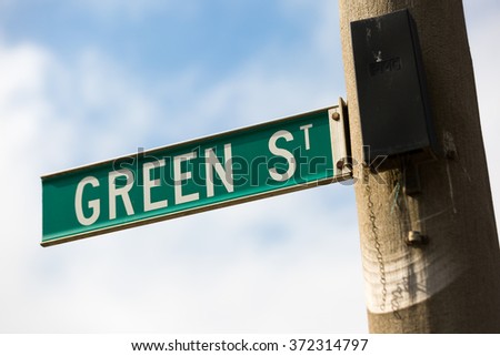 A green street sign with white lettering with the words - 'Green St'