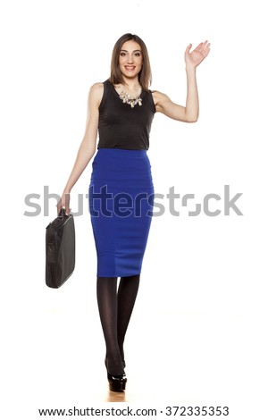 Young business woman walking with laptop bag and waving hand