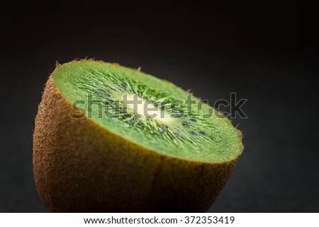 Ripe kiwi fruit, half full on dark background. Selective focus with shallow depth of field.