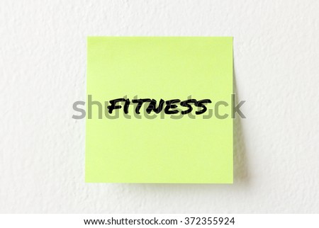 Yellow note paper with words Fitness on the white wall
