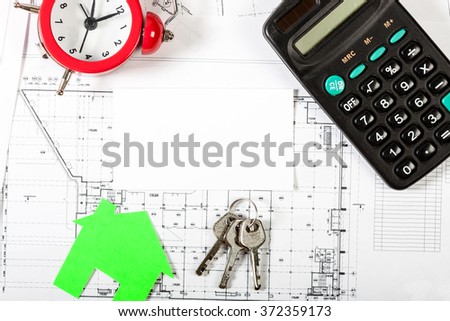 Model house on construction plan for house building, keys, red alarm clock and calculator. With white blank business card. Real Estate Concept.