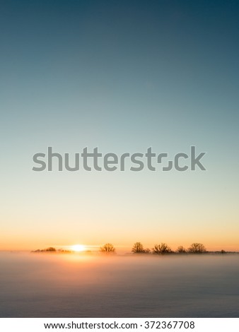 foggy country fields in winter on cold morning with snow