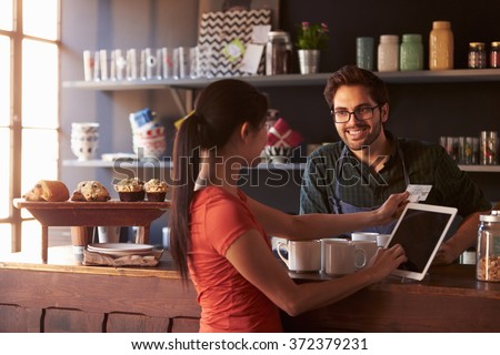 Customer In Coffee Shop Paying Using Digital Tablet Reader Royalty-Free Stock Photo #372379231